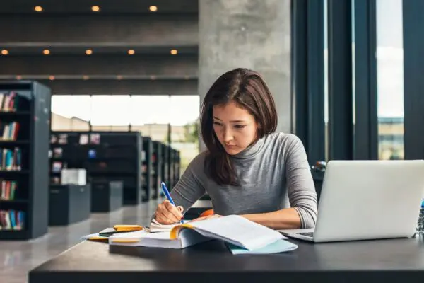 A woman sitting at a table writing on paper.